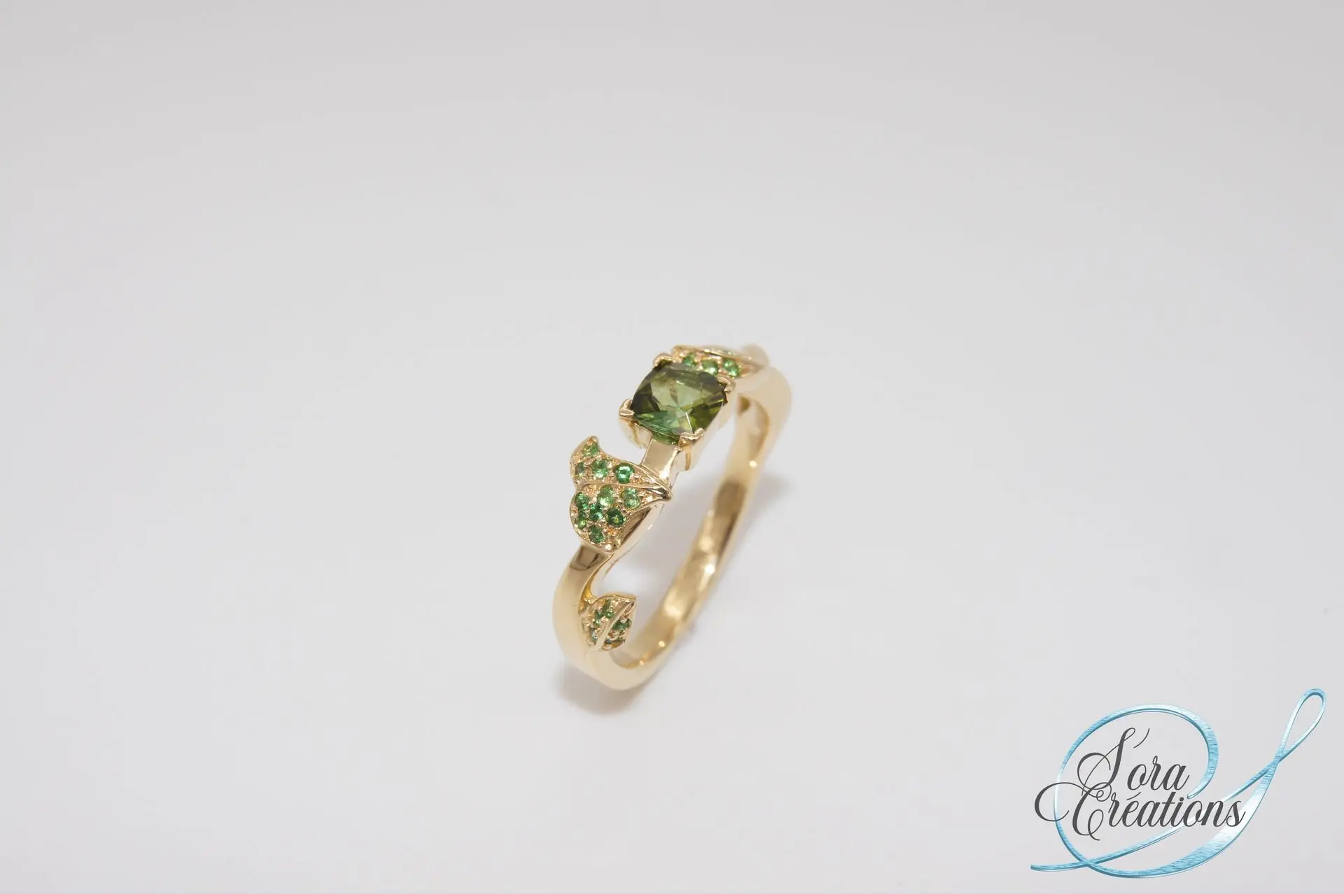 Bague sur-mesure en or jaune motif lierre avec une tourmaline verte et des grenats tsavorites et peridots