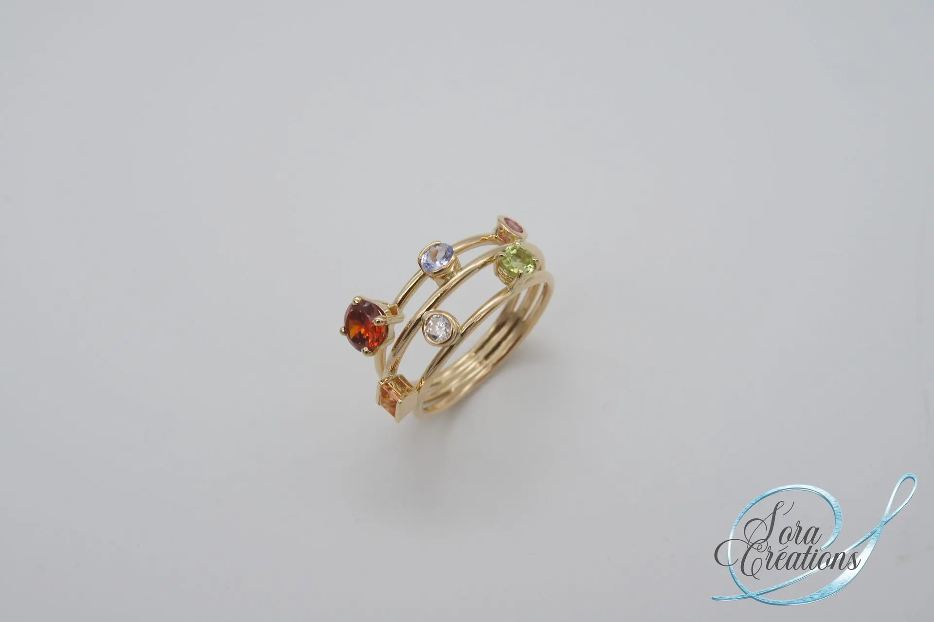 Bague sur-mesure fils en or jaune avec un saphir rose, un saphir bleu, un zircon et un grenat spessartite