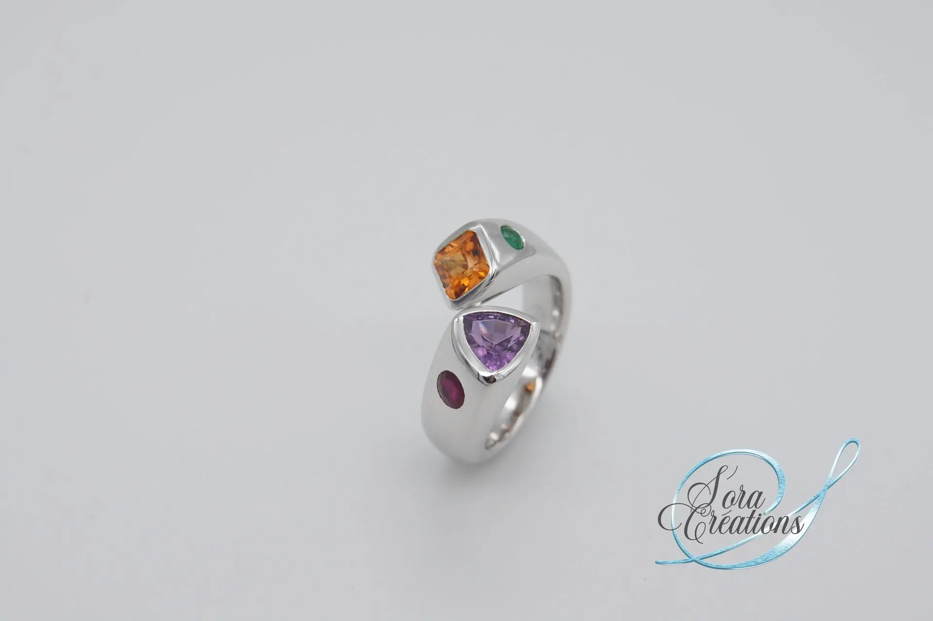 Bague sur-mesure toi&amp;moi en or gris avec un saphir violet, un grenat spessartite, un rubis et une émeraude